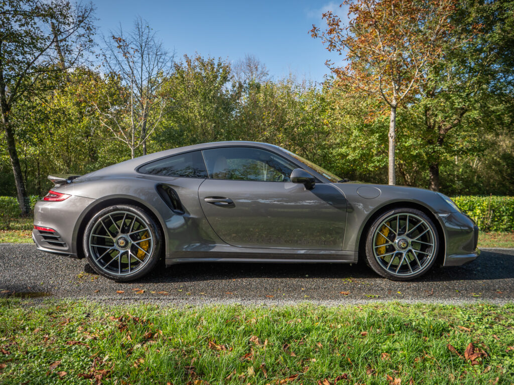 Vue latérale avec jantes sportives – PORSCHE – 911 991.2 – 2016 – Gris Quartz – 580 ch – Flat 6 Turbo – 36 900 km – Transmission : Sequentielle – Origine France – Privaty Cars – Reprise cash de voitures de luxe sans obligation d’achat en Charente-Maritime