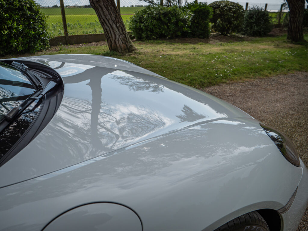 Capot avec reflets lumineux – PORSCHE – 718 CAYMAN – 2017 – Blanc Métallisé – 300 ch – Flat 4 Turbo – 28 900 km – Transmission : Sequentielle – Origine France – Privaty Cars – Dépôt-vente sécurisé de véhicules de prestige en Charente-Maritime