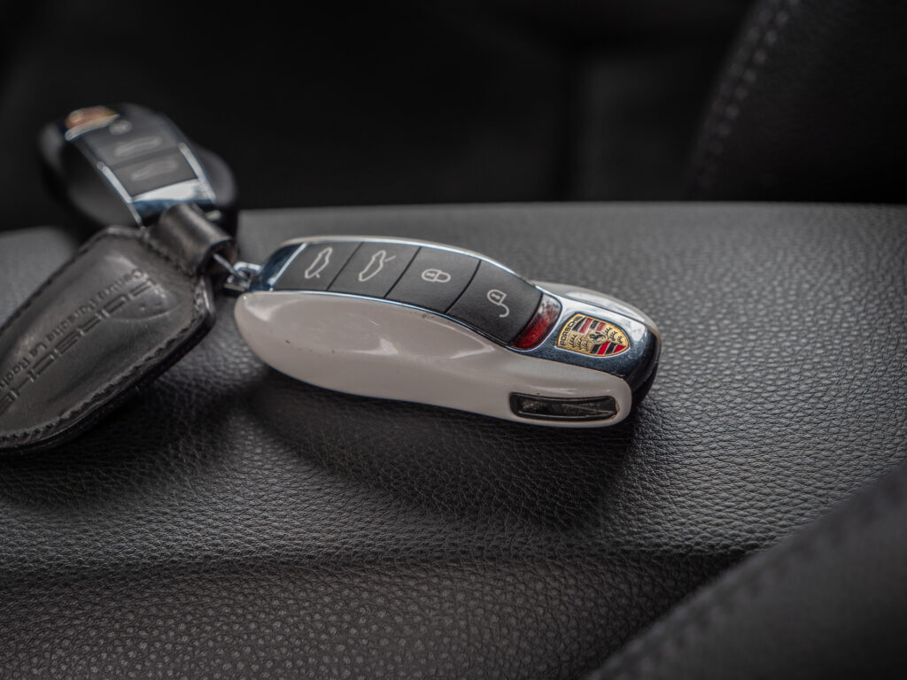 Clé de voiture sur cuir noir – PORSCHE – 718 CAYMAN – 2017 – Blanc Métallisé – 300 ch – Flat 4 Turbo – 28 900 km – Transmission : Sequentielle – Origine France – Privaty Cars – Dépôt-vente de voitures de sport et véhicules d’exception en Nouvelle-Aquitaine