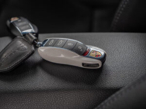 Clé de voiture sur cuir noir – PORSCHE – 718 CAYMAN – 2017 – Blanc Métallisé – 300 ch – Flat 4 Turbo – 28 900 km – Transmission : Sequentielle – Origine France – Privaty Cars – Dépôt-vente de voitures de sport et véhicules d’exception en Nouvelle-Aquitaine