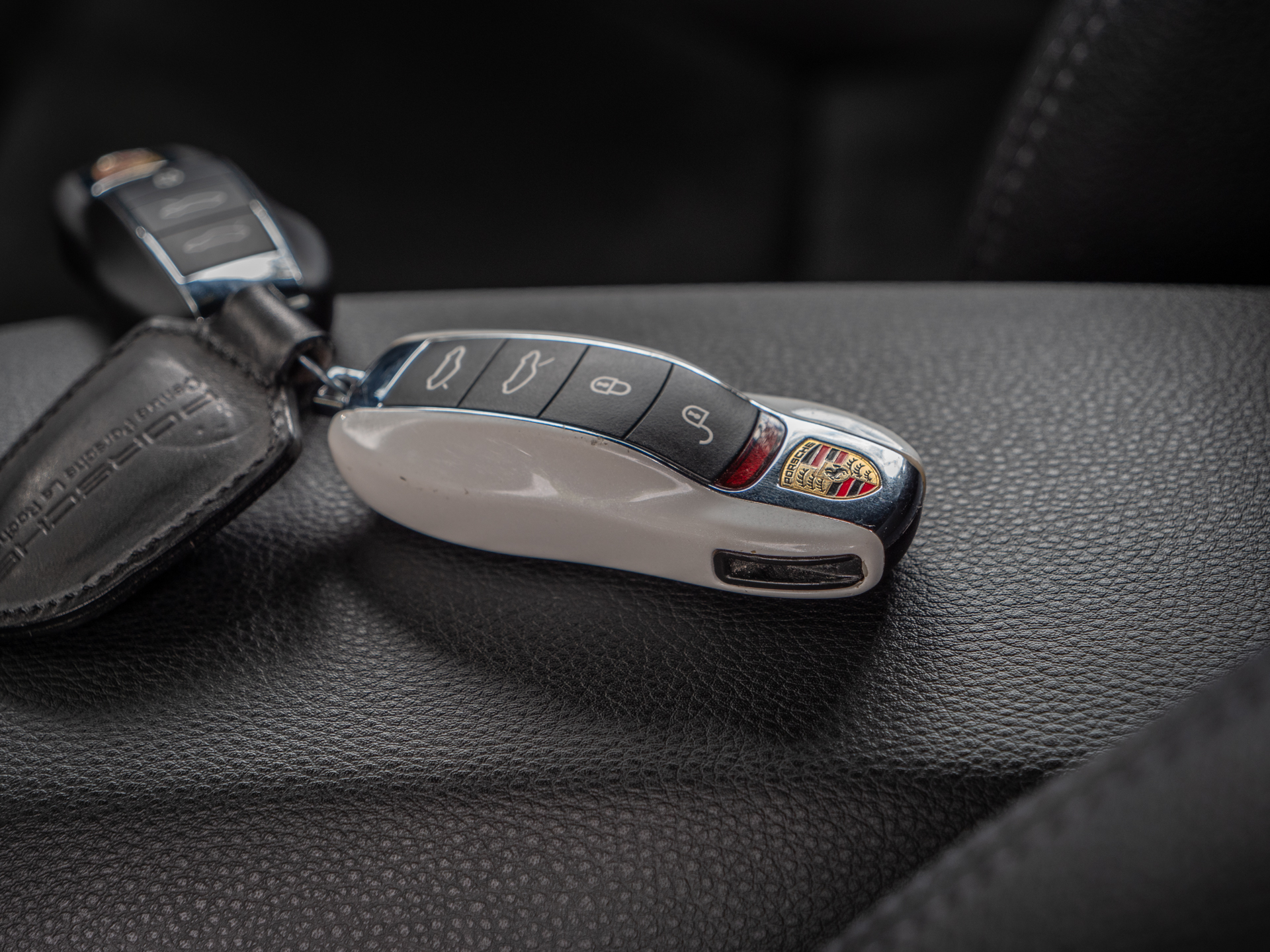Clé de voiture sur cuir noir – PORSCHE – 718 CAYMAN – 2017 – Blanc Métallisé – 300 ch – Flat 4 Turbo – 28 900 km – Transmission : Sequentielle – Origine France – Privaty Cars – Dépôt-vente de voitures de sport et véhicules d’exception en Nouvelle-Aquitaine