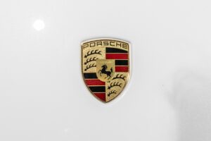 Emblème doré sur carrosserie blanche – PORSCHE – 911 992 CARRERA 4S – 2019 – Blanc Nacré – 18 900 km – 450 ch – Flat 6 Atmo – Transmission : Sequentielle – Origine France – Privaty Cars – Vente de supercars d’occasion proche de Bordeaux