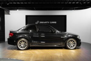 Vue latérale avec jantes en alliage – BMW – 1M – 2012 – Noir Saphirschwarz Metallic – 47 900 km – 340 ch – 6 cylindres en ligne bi-turbo – Transmission : Manuelle – Origine France – Privaty Cars – Chasseur de voitures de sport sur mesure près de Poitiers