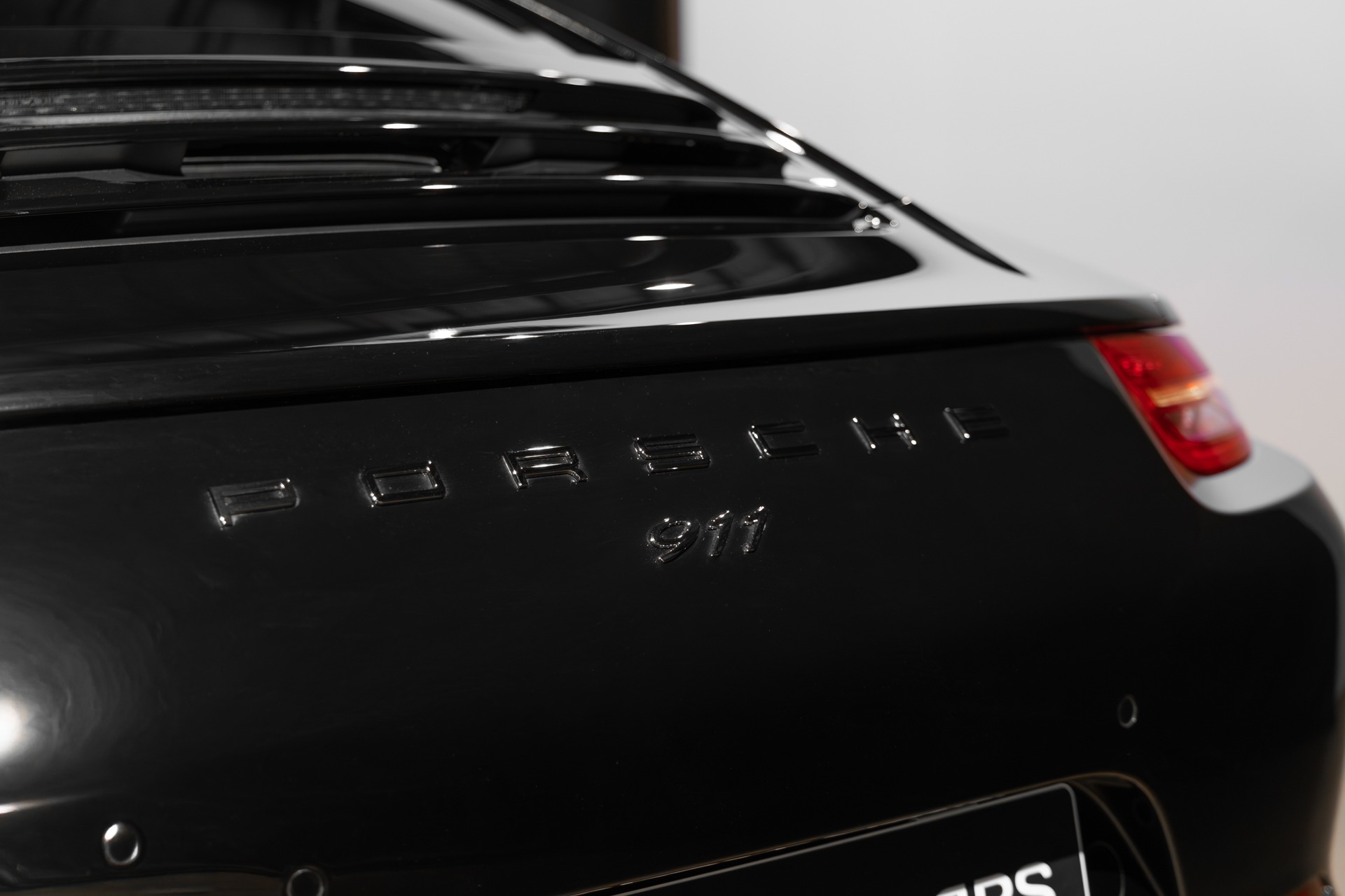 Logo arrière avec inscription 911 – PORSCHE – 911 991 CARRERA S – 2015 – Noir – 97 900 km – 400 ch – Flat 6 Atmo – Transmission : Sequentielle – Origine France – Privaty Cars – Vente de supercars d’occasion à 2 heures de Paris en TGV