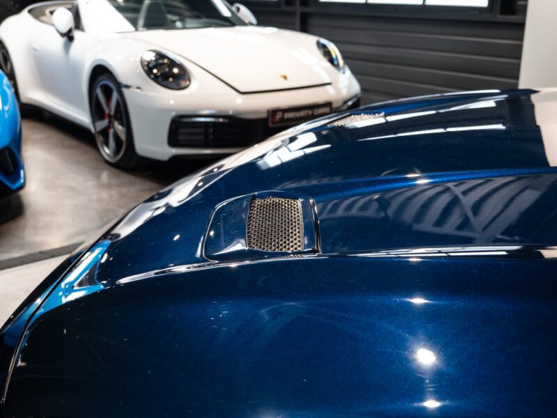 Entrée d'air sur le capot – PORSCHE – Ford Mustang V8 – 2019 – Bleu Kona – 48 900 km – 450 ch – V8 Atmo – Transmission : Manuelle – Origine France – Privaty Cars – Vente de voitures de prestige d’occasion en Charente-Maritime