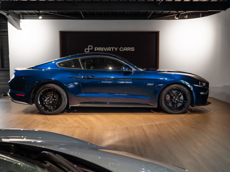 Vue latérale avec jantes noires – PORSCHE – Ford Mustang V8 – 2019 – Bleu Kona – 48 900 km – 450 ch – V8 Atmo – Transmission : Manuelle – Origine France – Privaty Cars – Dépôt-vente de véhicules PORSCHE près de Niort