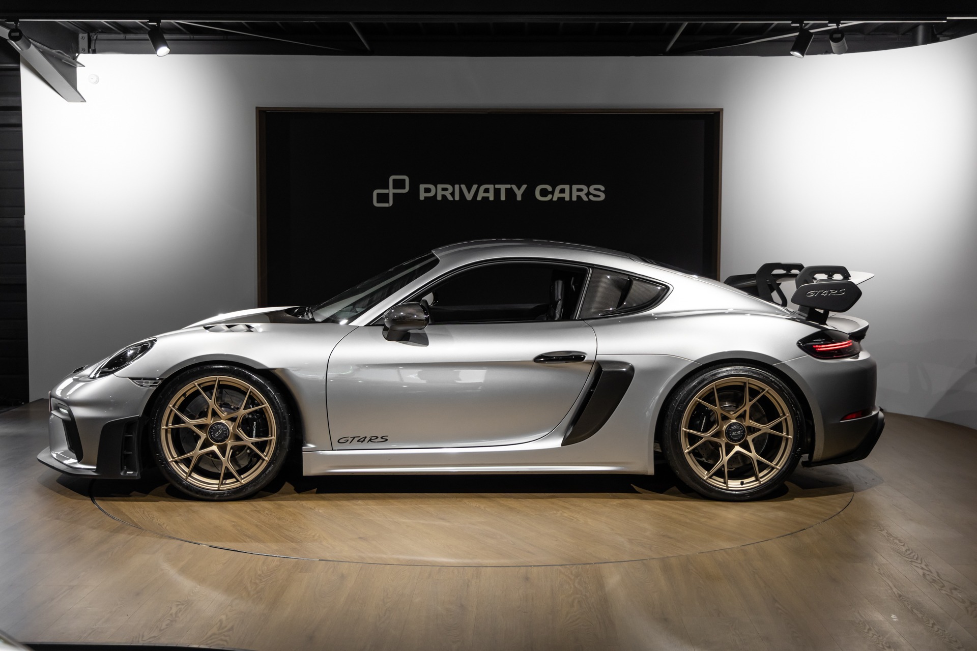 Vue latérale avec jantes dorées – PORSCHE – 718 GT4RS – 2024 – Gris Argent GT – 12 900 km – 500 ch – Flat 6 Atmo – Transmission : Sequentielle – Origine France – Privaty Cars – Sélection de véhicules PORSCHE disponibles près de Niort