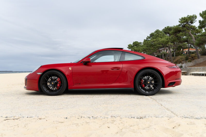 Vue latérale avec jantes noires – PORSCHE – 911 991.2 GTS – 2017 – Rouge Carmin – 100 900 km – 450 ch – Flat 6 bi-turbo – Transmission : Sequentielle – Origine France – Privaty Cars – Achat et vente de supercars d’occasion proche de Bordeaux
